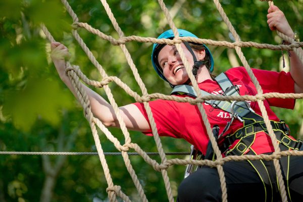 A woman climbing a rope net.